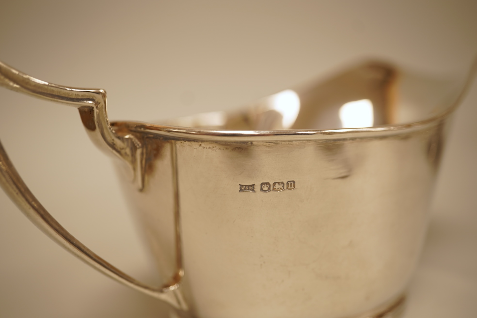A pair of George V silver sauceboats by Walker & Hall, Sheffield, 1929/30, length 17.9cm together with a George V silver sauceboat with flying scroll handle, William Comyns & Sons Ltd, London 1926, 16.4oz.